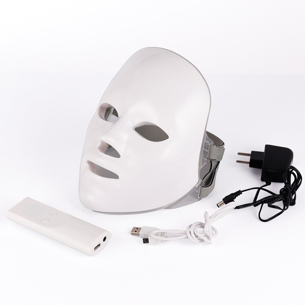 White LED face mask with power adaptor, USB cable, and remote control on a white background